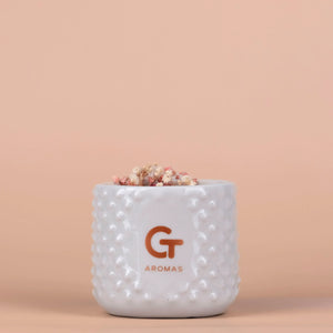 Vela aromática sostenible GT Aromas en vaso cerámico, flores secas, fondo beige elegante