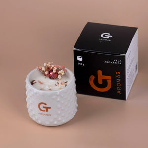 Vela aromática GT Aromas en vaso blanco con flores secas y caja negra, fragancias sostenibles.